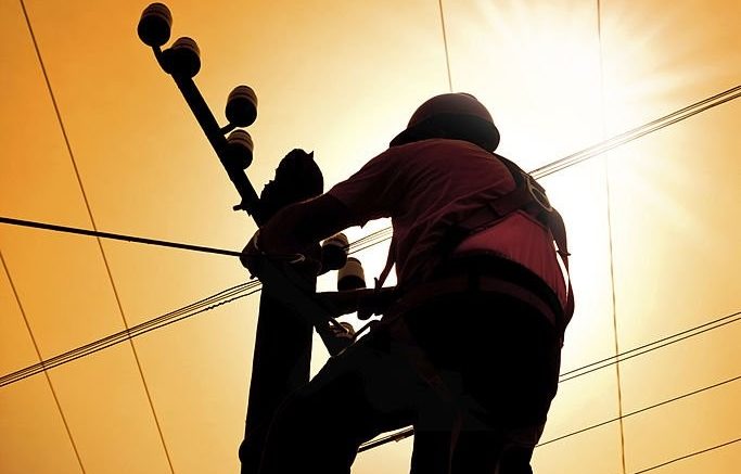 silhouette of electrician doing maintenance on power line pylon